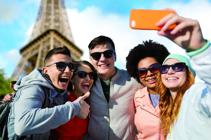 Estudiantes felices tomando un selfie frente a la Torre Eiffel