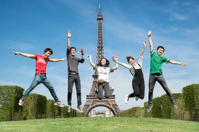 Estudiantes internacionales felices Estudiantes Internacionales en Francia, saltando de felicidad frente a la Torre Eiffel
